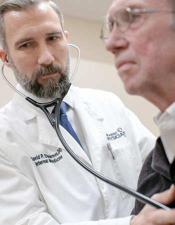 David Stearnes, DO, listens to John Emery's chest.