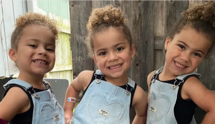 Three little triplet girls smiling at the camera.